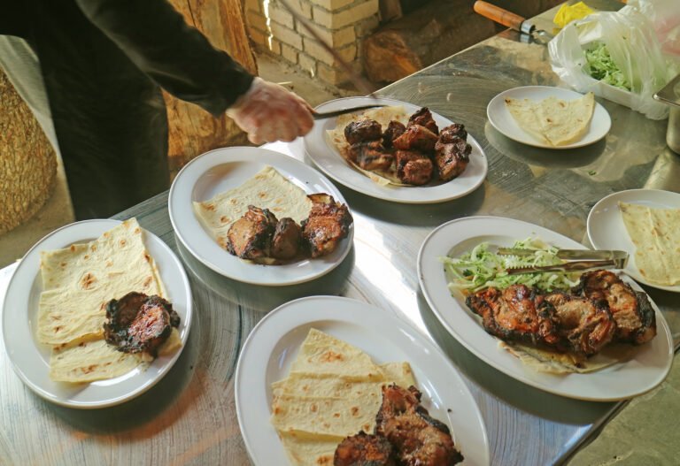 A chef taking grilled meat from the skewer while serving Armenian khorovats